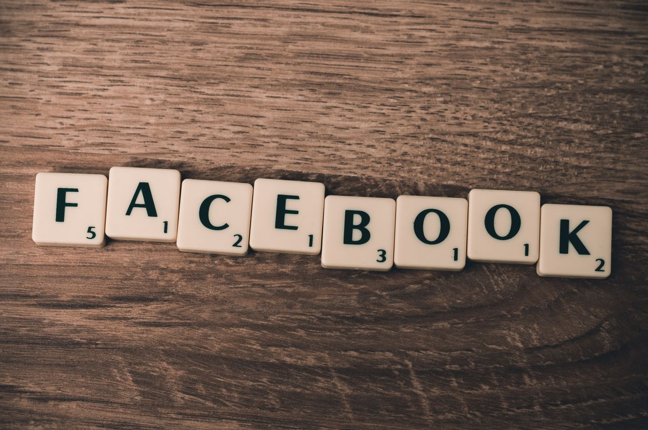 Scrabble tiles arranged to spell Facebook on a wooden surface, evoking social media.