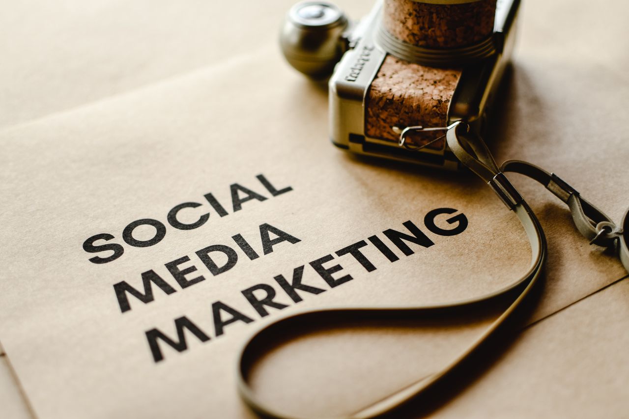 Vue rapprochée d’un appareil photo posé sur du papier brun avec le texte Social Media Marketing, mettant en avant les thèmes du marketing digital.
